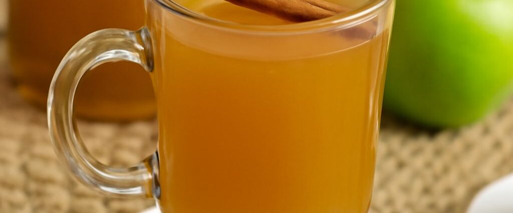 Homemade apple cider in a pot with apple slices and spices