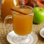 Homemade apple cider in a pot with apple slices and spices