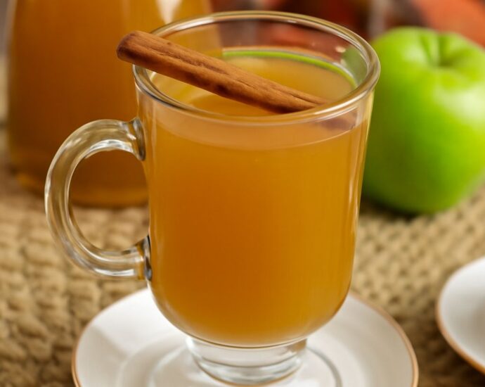 Homemade apple cider in a pot with apple slices and spices