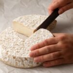Assorted slices and blocks of the best vegan cheeses, including cheddar and non-dairy options, on a wooden board