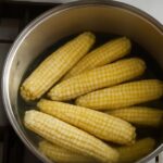 Blanching corn for freezing with corn ears, pot, and ice bath