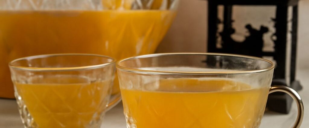 A glass pitcher of homemade fruit punch with citrus slices and ice