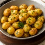 Crispy garlic parmesan potatoes in a serving bowl with fresh herbs
