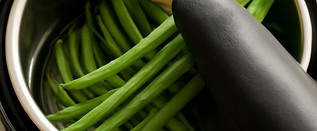 Jarred green beans with canning tools and fresh beans