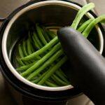 Jarred green beans with canning tools and fresh beans