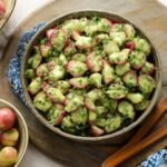 Mustard potato salad in a serving bowl with chopped herbs
