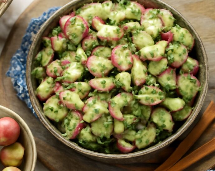 Mustard potato salad in a serving bowl with chopped herbs