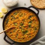 Red lentil curry recipe served in a bowl with rice and herbs