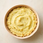 Mashed potatoes reheating in the oven in a covered baking dish