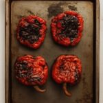 Charred roasted peppers on a tray after roasting