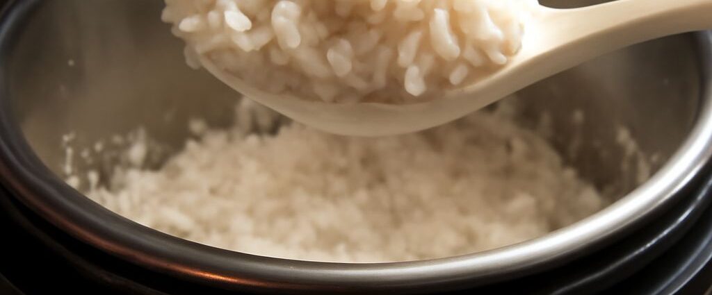 Sushi rice in a rice cooker with a wooden spoon