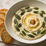 Creamy vegan dip in a bowl with herbs and crackers