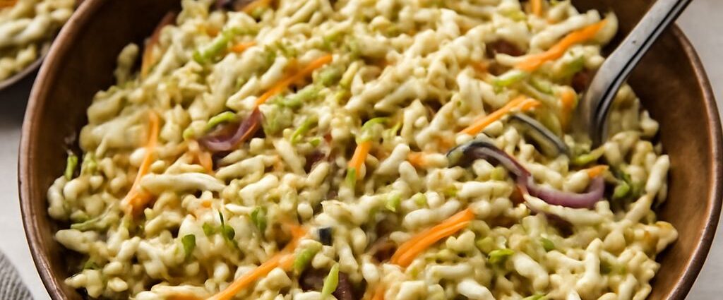 Broccoli slaw with ramen noodles, sunflower seeds, and tangy dressing in a serving bowl