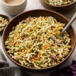 Broccoli slaw with ramen noodles, sunflower seeds, and tangy dressing in a serving bowl