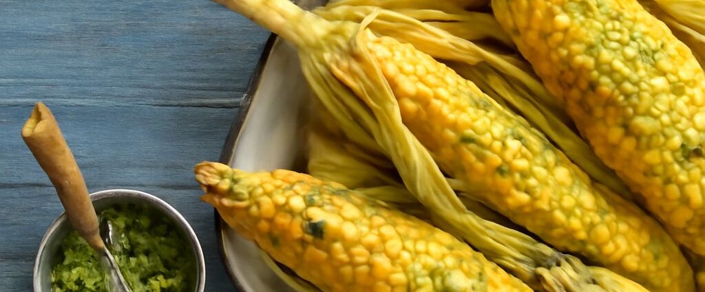 Sweet corn kernels beside popcorn and cornmeal representing corn’s grain, fruit, and vegetable contexts