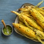 Sweet corn kernels beside popcorn and cornmeal representing corn’s grain, fruit, and vegetable contexts