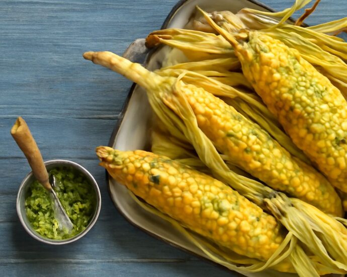 Sweet corn kernels beside popcorn and cornmeal representing corn’s grain, fruit, and vegetable contexts