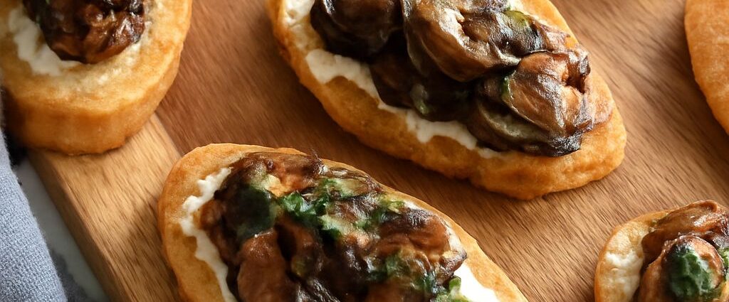 A platter of stuffed mushroom caps, mushroom crostini, skewers, and warm mushroom dip