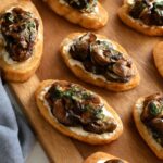 A platter of stuffed mushroom caps, mushroom crostini, skewers, and warm mushroom dip
