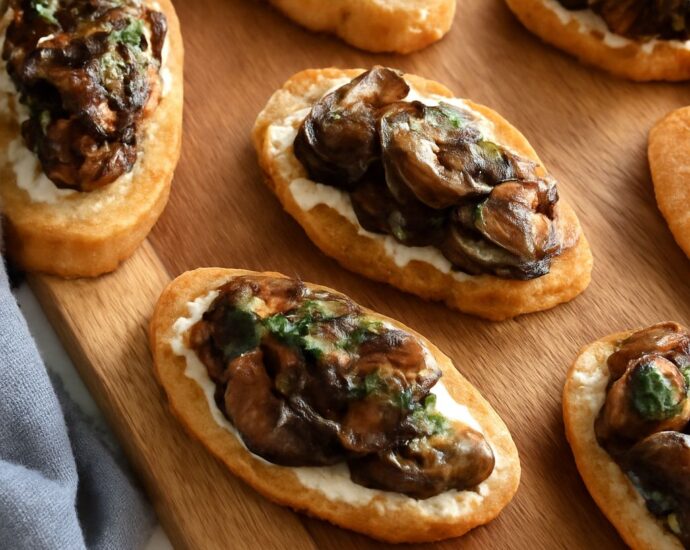A platter of stuffed mushroom caps, mushroom crostini, skewers, and warm mushroom dip