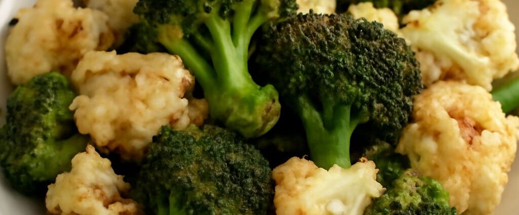 Roasted broccoli and cauliflower florets with tender centers and browned edges on a sheet pan