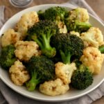 Roasted broccoli and cauliflower florets with tender centers and browned edges on a sheet pan