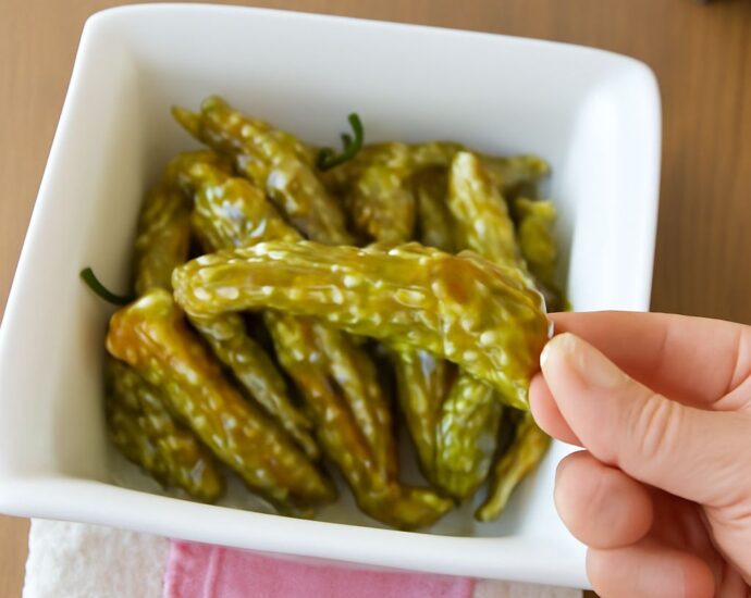 Blistered oven-roasted shishito peppers on a serving plate