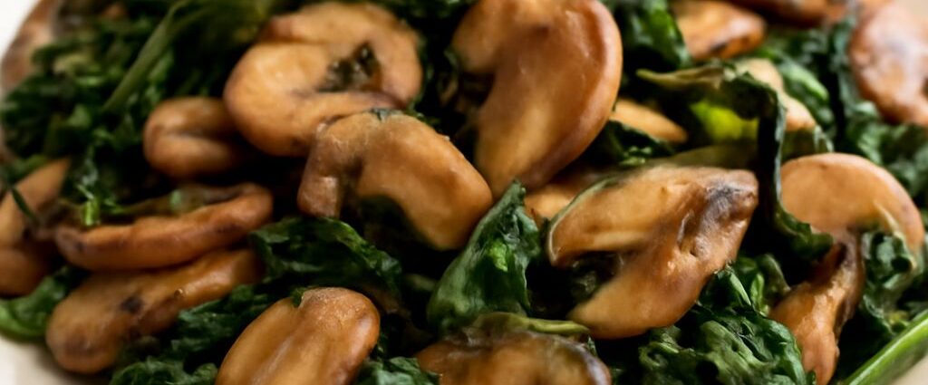 Browned mushrooms and wilted spinach in a garlic skillet