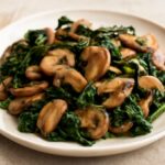 Browned mushrooms and wilted spinach in a garlic skillet