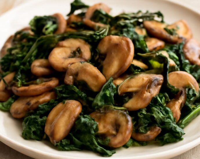 Browned mushrooms and wilted spinach in a garlic skillet
