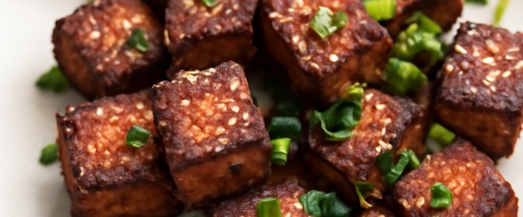 Packaged silken and firm tofu beside cooked tofu pieces