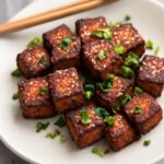 Packaged silken and firm tofu beside cooked tofu pieces