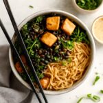Vegetarian tofu ramen bowl topped with browned tofu, noodles, greens, and sesame