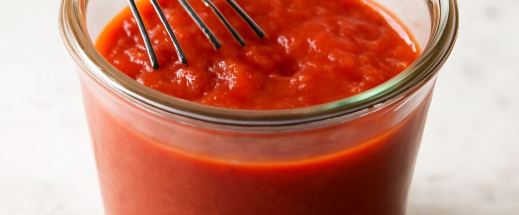 Thick tomato paste pizza sauce spread over pizza dough