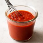 Thick tomato paste pizza sauce spread over pizza dough