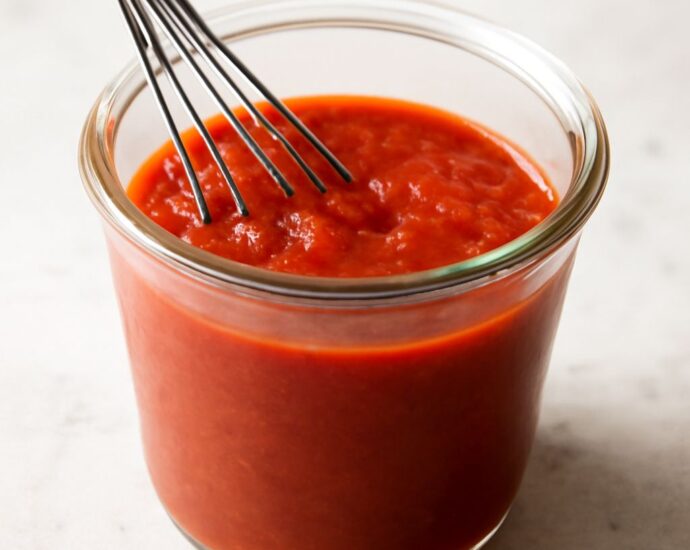 Thick tomato paste pizza sauce spread over pizza dough