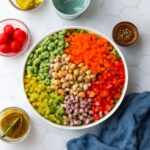 Vegan salad recipe with quinoa, chickpeas, greens, vegetables, and tahini dressing
