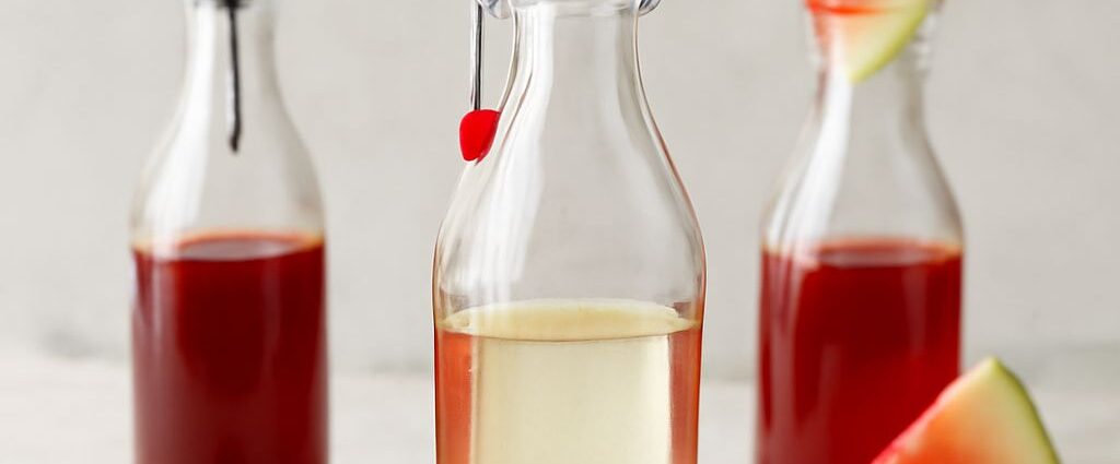 A jar of simple syrup with a spoon and ingredients for making simple syrup.
