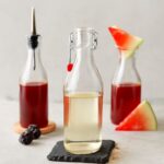 A jar of simple syrup with a spoon and ingredients for making simple syrup.