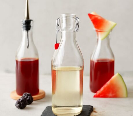 A jar of simple syrup with a spoon and ingredients for making simple syrup.